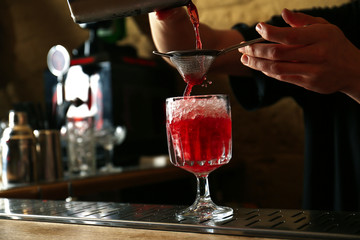 Bartender preparing fresh alcoholic cocktail at bar counter, closeup