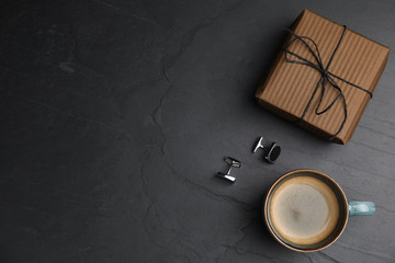 Cup of coffee, gift box and cuff links on black table, flat lay with space for text. Happy father's day