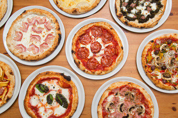 Table with pizzas of varied flavors, view from above.
