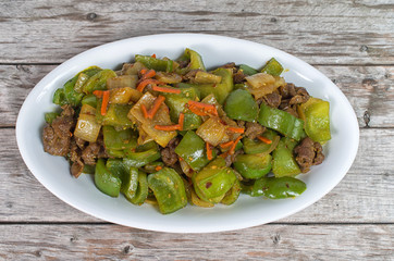 Stir fried beef and green peppers dish on a wooden table
