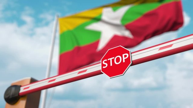 Closing boom barrier with stop sign against the Myanma flag. Restricted border crossing or certain ban in Myanmar