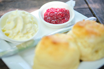 Fresh baked scones with jam and cream served on an old style table at cafe