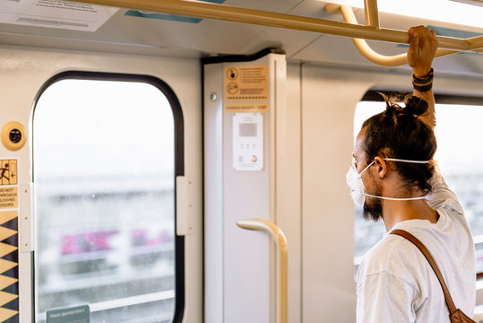 A Young Man With A Bun Is Wearing A Mask In The Subway