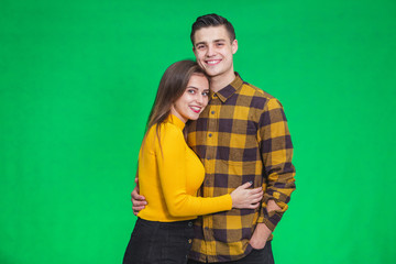 Stylish couple in autumn outfits posing isolated on green background.