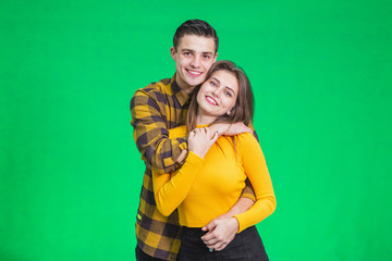 Stylish couple in autumn outfits posing isolated on green background.