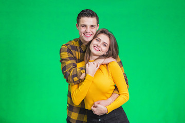 Stylish couple in autumn outfits posing isolated on green background.