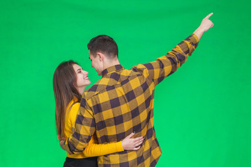 Handsome boyfriend shows his girl a beautiful scene, pointing at it, while they are standing back to the camera.