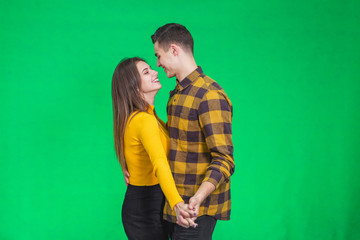 Lovely portrait of happy young couple in love embracing each other over green background.