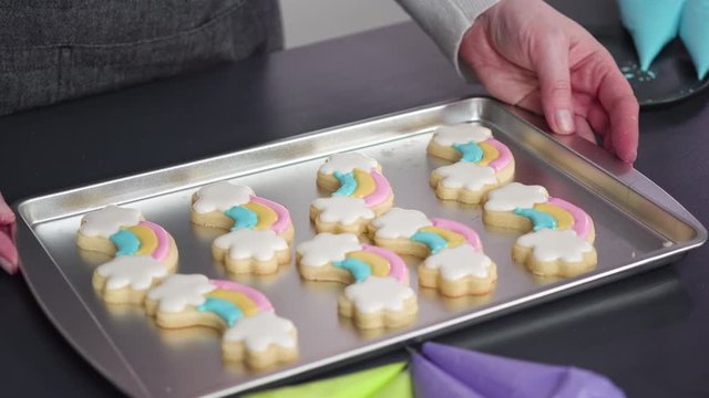 Decorating unicorn sugar cookies with multi-color royal icing.