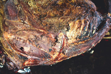 Different stages of cooking the steak on a kitchen, barbeque, roasted lamb ribs, big dish plate with roasted full pork head, served in restaurant with vegetables, lamb, ham and chicken.
