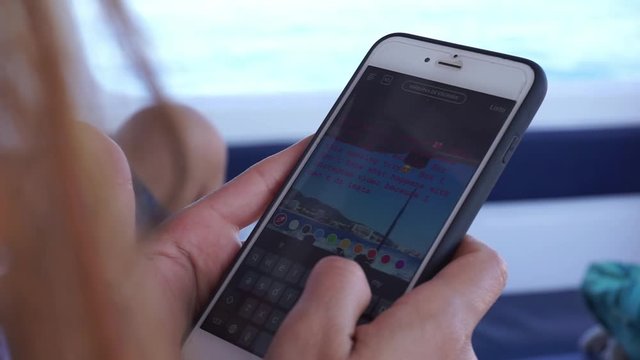 Girl texting a story on Instagram of her vacation in a boat