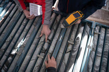 team of mining  workers measuring drilled rock core - obrazy, fototapety, plakaty