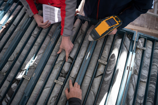 team of mining  workers measuring drilled rock core