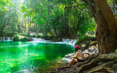 Traveler woman joy relaxing in beautiful green nature scenic landscape waterfall in deep tropical...