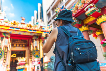 Obraz premium Traveler woman with backpack looking and taking photo Chinese shrine, Famous landmark travel Bangkok Thailand, Tourist female on summer holiday vacation trips, Tourism beautiful destination place Asia