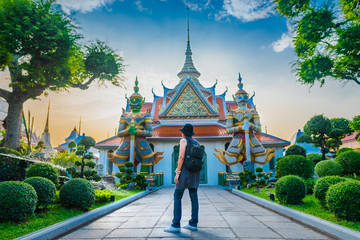 Traveler woman looking old temple in Wat Arun at evening sunset time, Popular famous landmark...