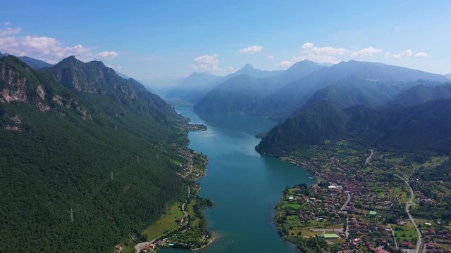 Panoramic view of the mountains and Lake Idro. The reflection in the water of the mountains, trees, blue sky. Aerial view