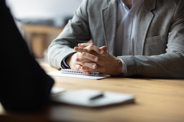 Two businessmen with clasped hands sitting opposite close up