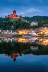 Cochem Castle, Germany, reflects in Moselle river with heritage European building and  cruises during twilight