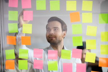 Confident businessman mentor writing on sticky papers, post it notes