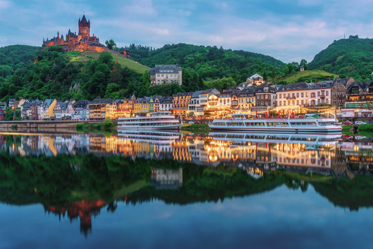 Cochem Castle, Germany, reflects in Moselle river with heritage European building and  cruises during twilight