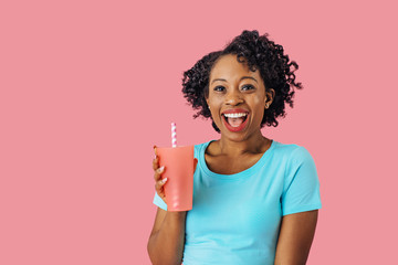 Close up portrait of an excited young smiling woman holding a drinking cup with straw and looking at camera  with mouth open - obrazy, fototapety, plakaty