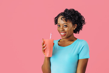 Close up portrait of a happy young smiling woman  holding a drinking cup with straw and looking at camera