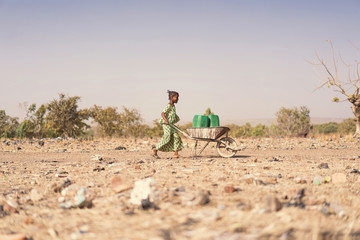 Tiny African Ethnicity Schoolgirl Engaged with nutritious Water for a lack of water symbol - obrazy, fototapety, plakaty
