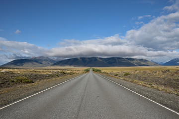 vista de carretera de asfalto con arboles montagnas y nubes de fondo