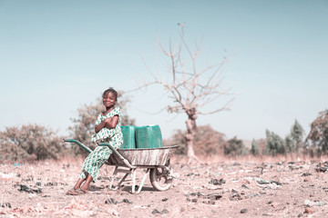 Cute West Africa Woman Transporting Clean Water with major difficulties