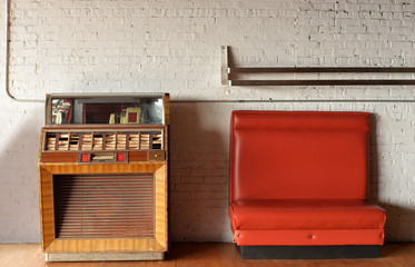 vintage jukebox and bench against brick wall