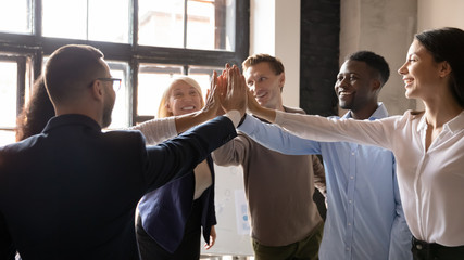 Group successful multiethnic workmates giving high five celebrating career growth
