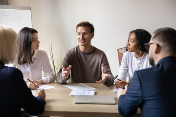 Diverse businesspeople listen team leader seated at table in office