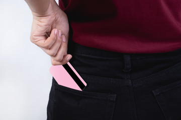 A girl wearing a red shirt while holding a credit card in her hand with a white background The concept is to put a credit card in the pants pocket.