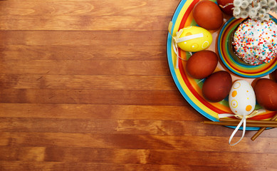 Easter cake with painted eggs on a table made of natural wood.