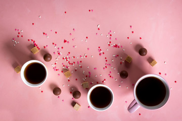 Coffee tea cups, sweets candy chocolate on pink hearts background. Valentines day 14 february minimal concept