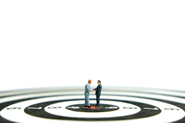 Business strategy conceptual photo - Miniature of businessman make an handshake partnership above dartboard with white background 