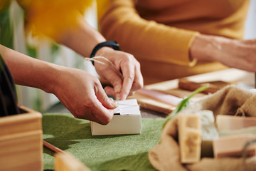 Women packing small soap bars in cardboard boxes to send it to customers