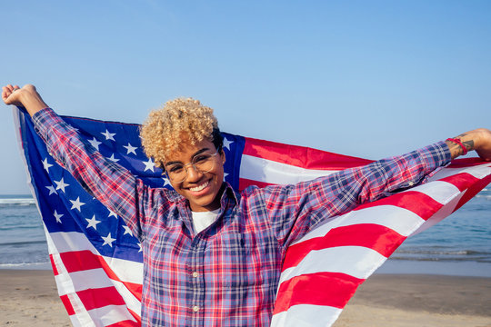 happy afro american woman holding usa flag at sunny tropical beach.4th of July Independence Day concept