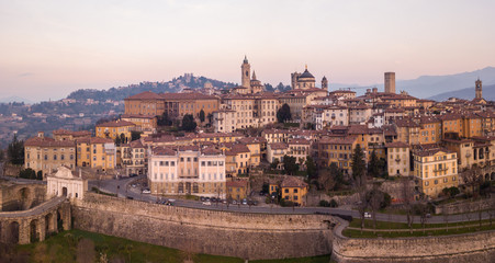 Fototapeta na wymiar Bergamo, Italy. Drone aerial view of the old town during sunrise. Landscape at the city center, its historical buildings and the Venetian walls a Unesco world heritage