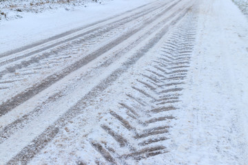 Tire tracks on icy road covered with snow