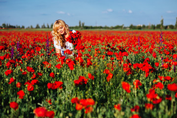 cheerful girl with curly blond hair in a huge poppy field alone, springtime, sunset