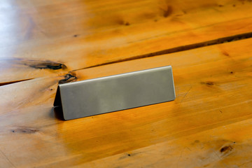 Blank metallic table top desk identification nameplate on a wooden desk
