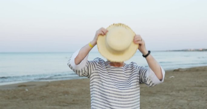 Cheerful elderly woman on the sea beach early in the morning at sunrise.