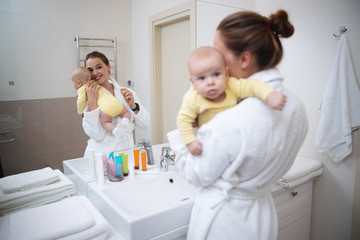 Fototapeta na wymiar Happy woman brushing teeth and holding her baby stock photo