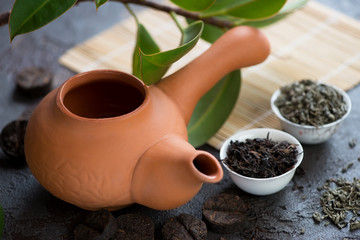 Fototapeta na wymiar Closeup of ceramic teapot and pialas with dry tea leaves, studio shot, selective focus