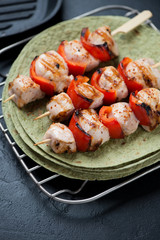 Closeup of chicken skewers with green tortilla flatbread, vertical shot, selective focus