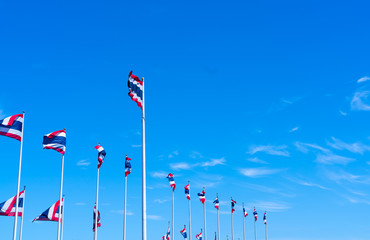 Many of Thailand flag waving on top of flagpole against blue sky. Thai flag was drawn to top of the flagpole. Red, blue, and white color rectangle fabric. National flag of the Kingdom of Thailand.
