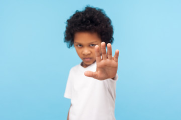 No, forbidden! Portrait of serious angry little boy with curly hair showing stop gesture, warning...