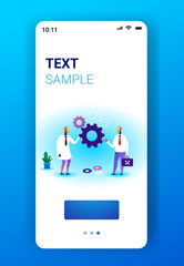 two robots holding cog wheel brainstorming process artificial intelligence technology teamwork concept smartphone screen mobile app vertical full length copy space vector illustration